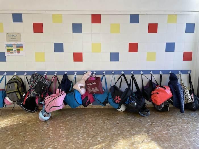 des cartables d'élèves du lycée français de Valence suspendus contre un mur