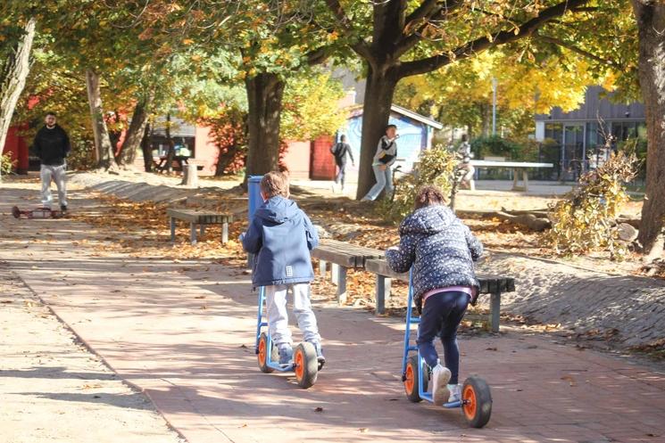 Deux enfants à trotinette dans une cours d'école