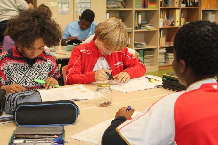 Trois élèves de primaire en train de faire des exercices.