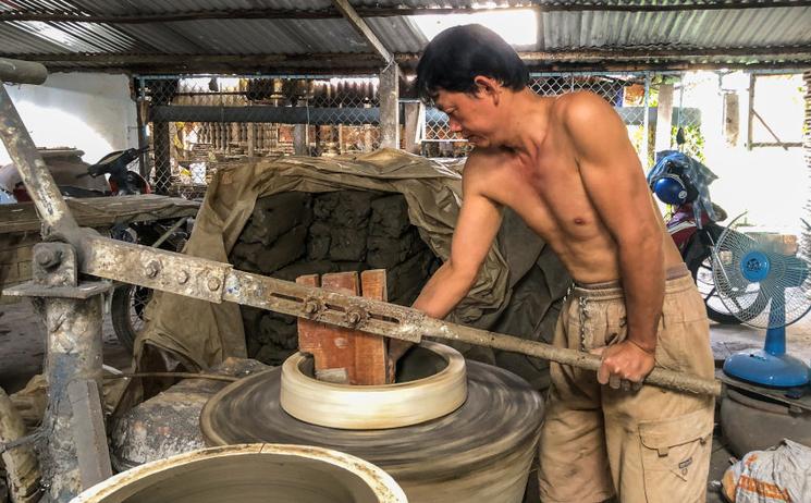 Ouvrier vietnamien qui travaille la terre pour la fabrication d'un pot