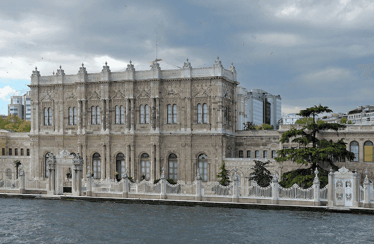 Vue extérieure du Palais de Dolmabahçe à Istanbul, avec son architecture élégante au bord du Bosphore sous un ciel nuageux.