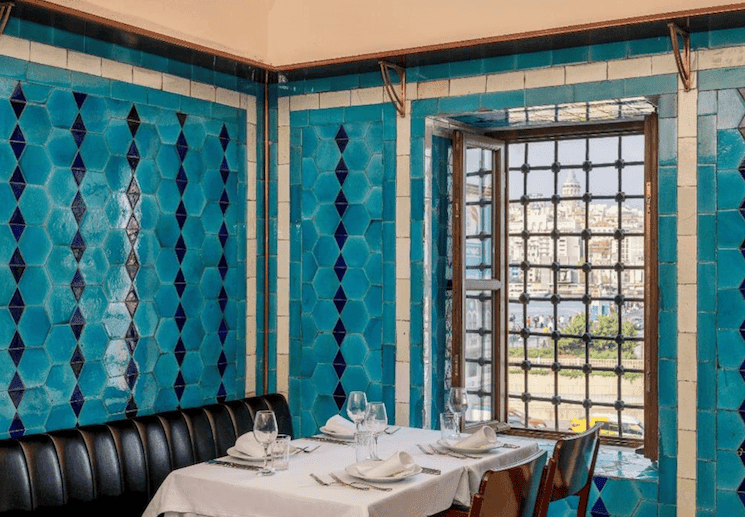 Intérieur du restaurant Pandeli à Istanbul, célèbre pour ses carreaux bleus emblématiques, avec une vue sur la Corne d’Or depuis le Grand Bazar.