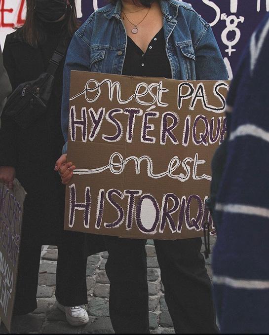 Une femme tenant un panneau disant "on est pas hystérique, on est hystorique", en manifestation féministe