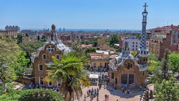 Parc Güell designé par gaudi : maisons arrondies, arbres et vue sur la ville