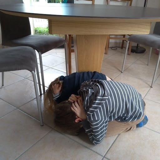Des enfants se mettent sous une table pendant un séisme