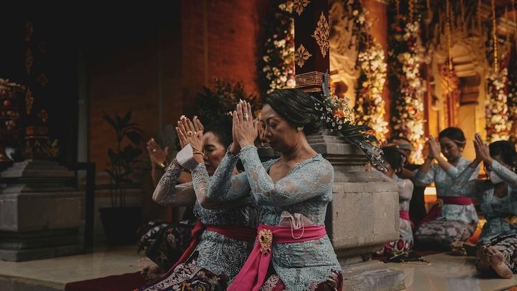 dames habillées en tenue traditionnelle bleu avec sarong rose qui prient les mains jointes dans un temple à bali en indonésie