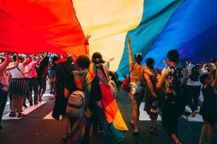 Des personnes sous un drapeau couleur arc-en-ciel pour la pride, jour de la fierté gay
