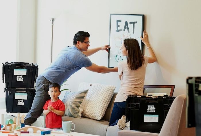 des personnes en train d'installer un tableau dans leur nouvel maison