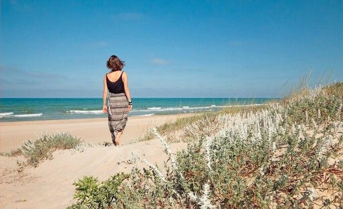 une femme en train de marcher dans le sable sur une plage de Valencia