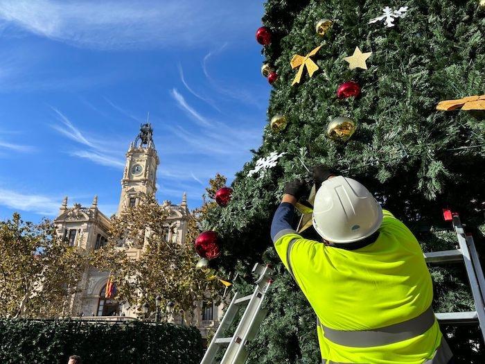 un ouvrier en train d'installer des décorations de Noel sur un sapin plaza del ayuntamiento à valencia