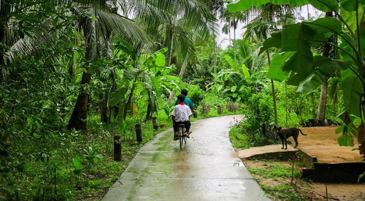 Sentier cocoteraie et enfants à vélo autour de Ben Tre au Vietnam