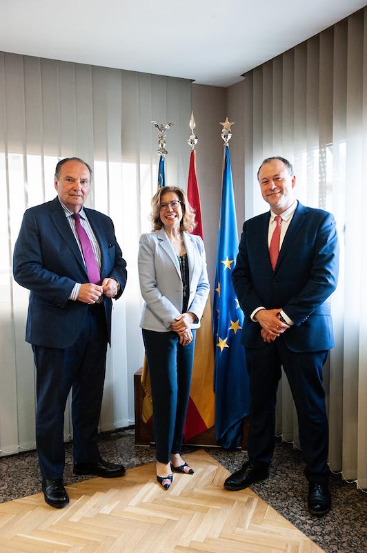 Deux hommes en costume et une femme devant des drapeaux à la camara de comercio devalencia