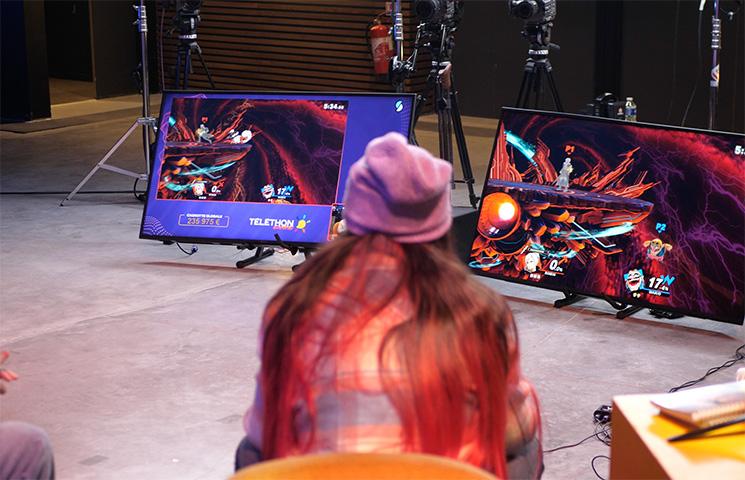 Personne assise devant un écran qui affiche le montant de la cagnotte du Téléthon Gaming
