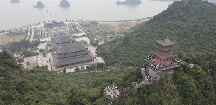 Touristes visitent la pagode au sommet de la montagne à Tam Chuc