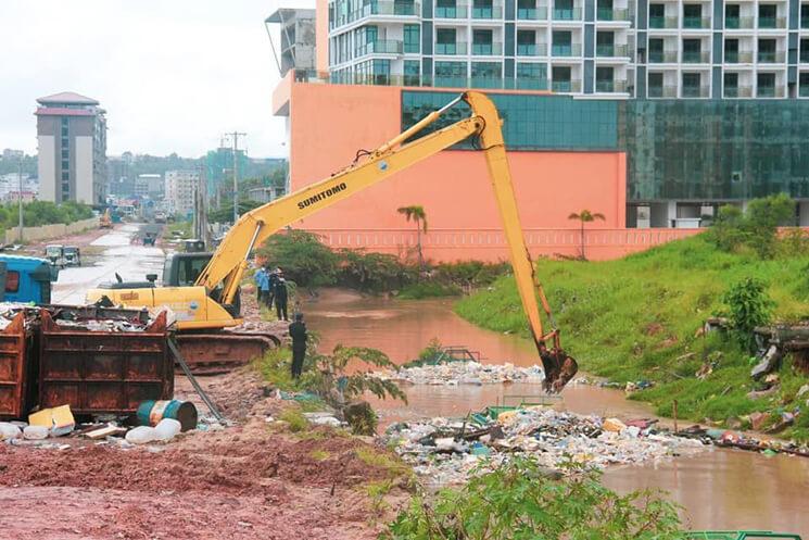 une pelleteuse dégages des canaux des ordures apres une inonation