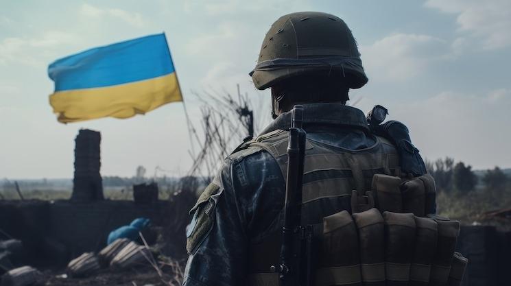 Un soldat ukrainien de dos avec un drapeau de l'Ukraine pendant la guerre contre la Russie, alors que Zelensky rencontre Macron à Paris