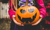 Un enfant déguisé tenant une citrouille pour Halloween