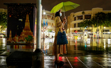 Une femme thailandaise sous la pluie dans les rues de Bangkok la nuit