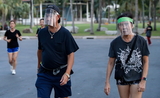 Des joggers portant des visieres anti-coronavirus dans un parc de Bangkok