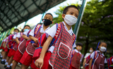 Des élèves thaïlandais masqués en rang à l'école