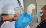 Une infirmiere effectue un prelevement nasal pour un test Sars-Cov-2