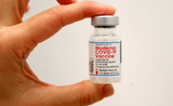 Une personne tient dans sa main une dose du vaccin Moderna