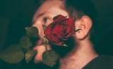 Un homme tenant une rose entre ses lèvres