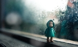 Une figurine sous un anorak sous un ciel pluvieux 