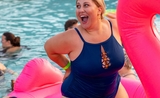 Une femme dans une piscine, sur une grande bouée, souriant largement