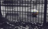 Un ballon de football derrière une grille