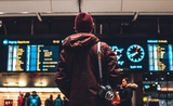 Un homme se tient devant les panneaux d'arrivées à l'aéroport 
