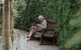Une personne âgée est assise sur un banc