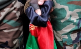 Deux personnes tenant un drapeau afghan dans leurs mains.
