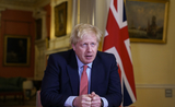Le Premier ministre britannique Boris Johnson à son bureau avec un drapeau anglais en fond