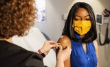 Une jeune femme avec un masque se faisant vacciner contre le COVID-19