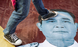 Un manifestant thailandais pose le pied sur la photo du Premier ministre Prayuth Chan-O-Cha