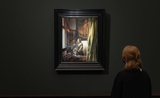 Une personne devant le tableau La Liseuse à la fenêtre de Vermeer dans l'exposition à la Gemaldegalerie de Dresde
