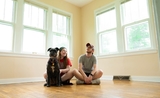 un homme, une femme et un chien assis à même le sol dans une pièce vide