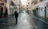 Une femme se promenant dans une rue à Rome avec un masque