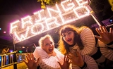 Deux femmes devant l'inscription lumineuse "Fringe World"