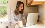 une femme consulte son ordinateur, dans son logement, en Espagne