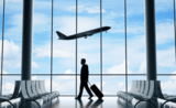 Un homme marchant dans un aéroport tandis qu'un avion prend son envol