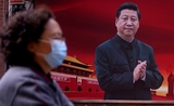 Une femme avec un masque face à une affiche de Xi Jinping