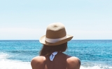 Une femme avec un chapeau face a la mer a Valence