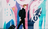 Un jeune homme marche dans la rue en tirant sa valise