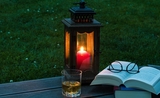 Une lanterne brille sur une petite table près d'un livre 