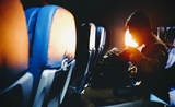 Un homme cherche dans son sac son ordinateur dans un avion à destination de l'australie