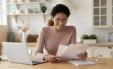 Femme souriante avec ordinateur lisant un papier  