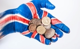 Une main peinte tient des pièces de monnaie britannique
