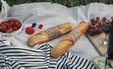Une baguette, un verre de vin, des fruits, du fromage et un drapeau français
